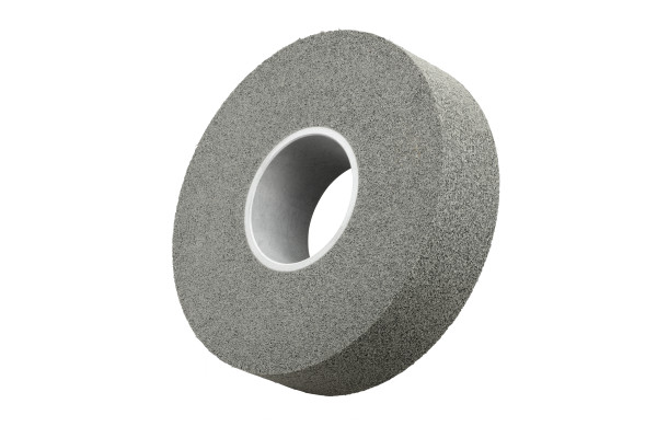 Eine graue, runde 3M XL-WL Kompaktscheibe für Entgratungs- und Finisharbeiten, aus gewickeltem Faservliesmaterial mit Aluminiumoxid-Korn. Sie hat eine zylindrische Bohrung in der Mitte und eine raue, abrasive Oberfläche. Isoliert auf weißem Hintergrund.