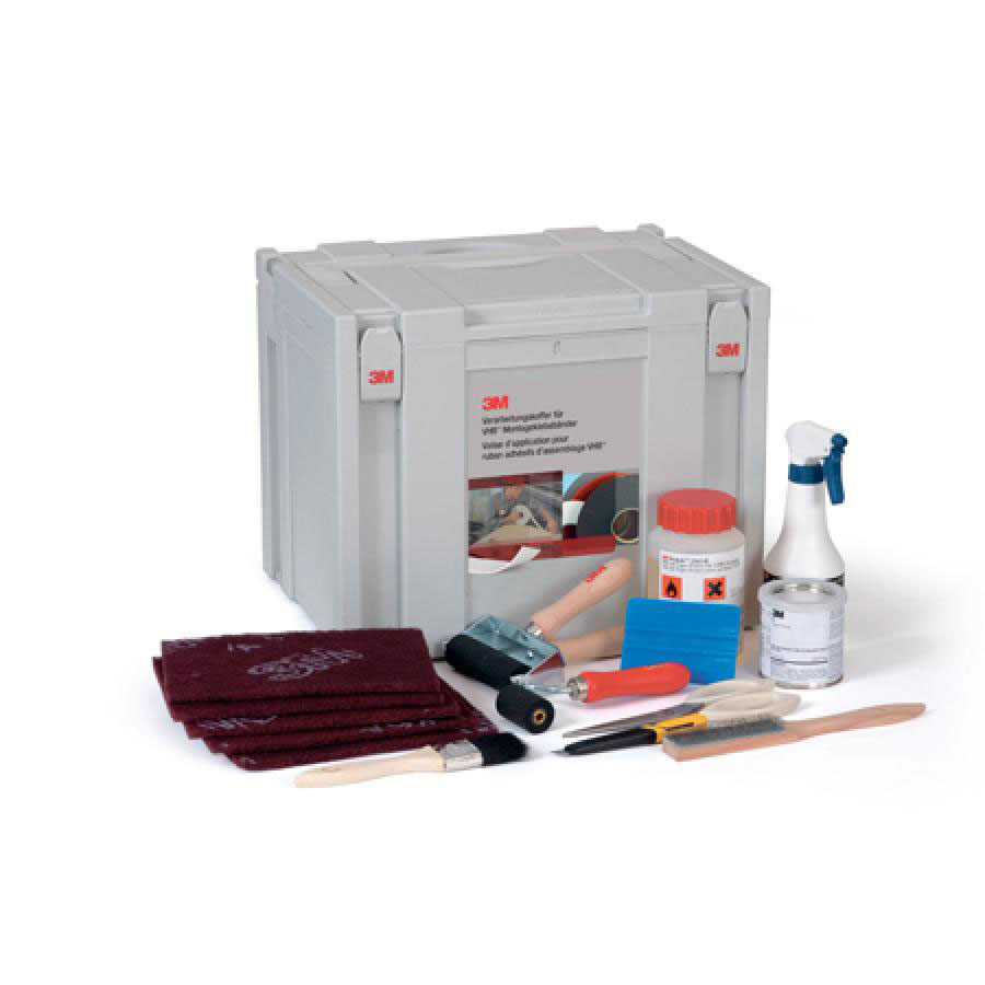 Mallette de travail 3M gris clair ouverte avec accessoires pour les collages VHB : toiles de nettoyage Scotch-Brite, 2 rouleaux de pression, raclette bleue, pinceau, couteau, vaporisateur, flacon pour produits dangereux, boîte métallique.